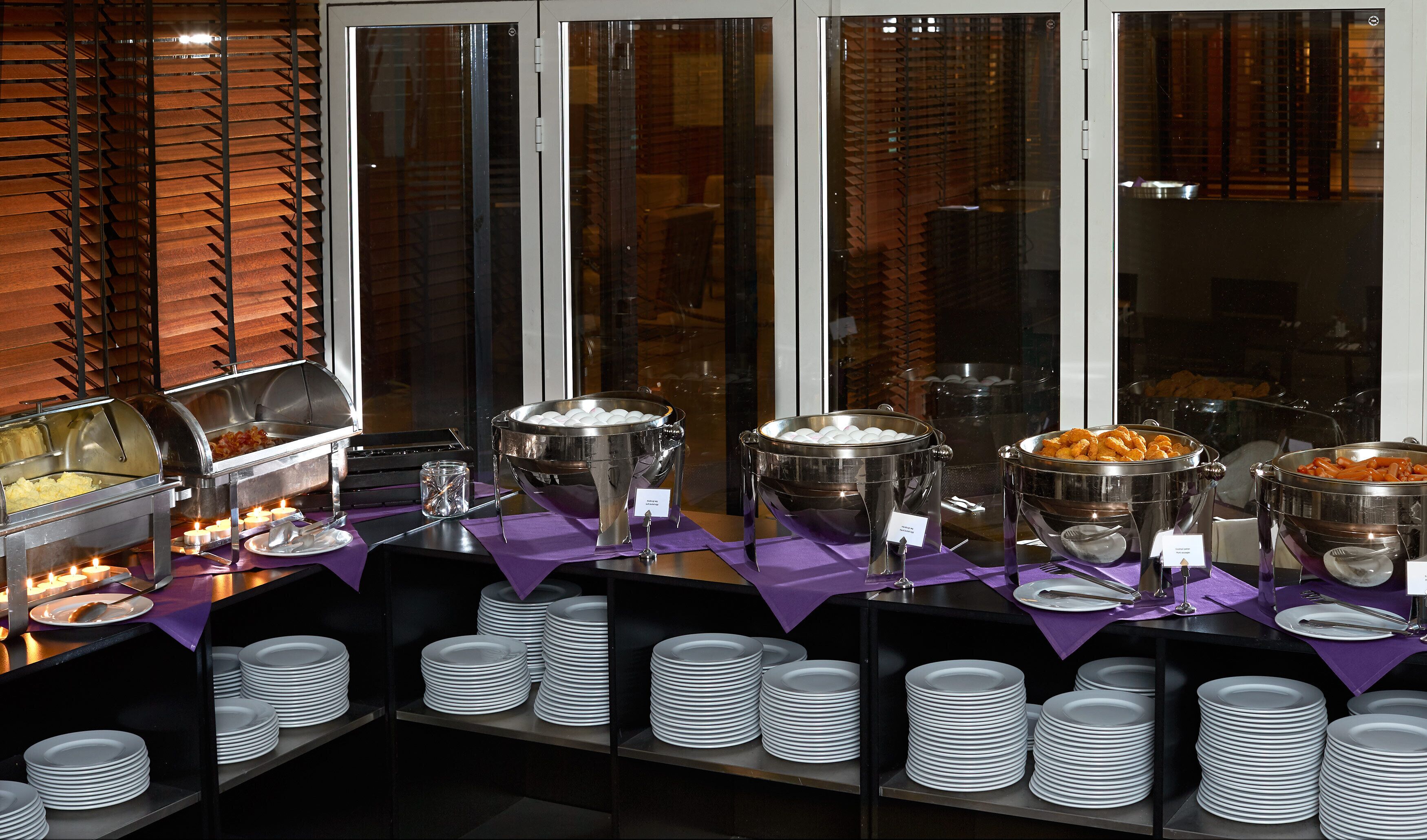Een buffetopstelling met diverse voedselcontainers en stapels borden.
