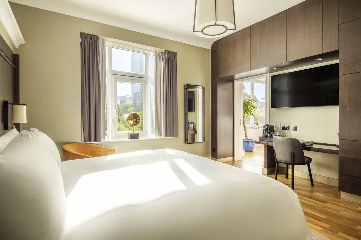 A modern hotel room with a large bed, a desk, and a TV.