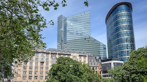 A modern building with a curved glass facade, surrounded by trees and other buildings. - DoubleTree by Hilton Brussels City (Brussels)