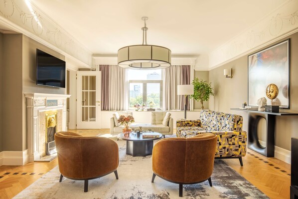 A living room with a fireplace, a television, a sofa, and two armchairs.