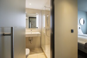 A modern bathroom with a glass shower enclosure, a sink, and a toilet. - Brussels Louise (Brussels)