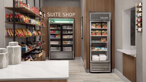 Tienda en una suite de hotel con estantes llenos de refrigerios, bebidas y artículos de tocador.
