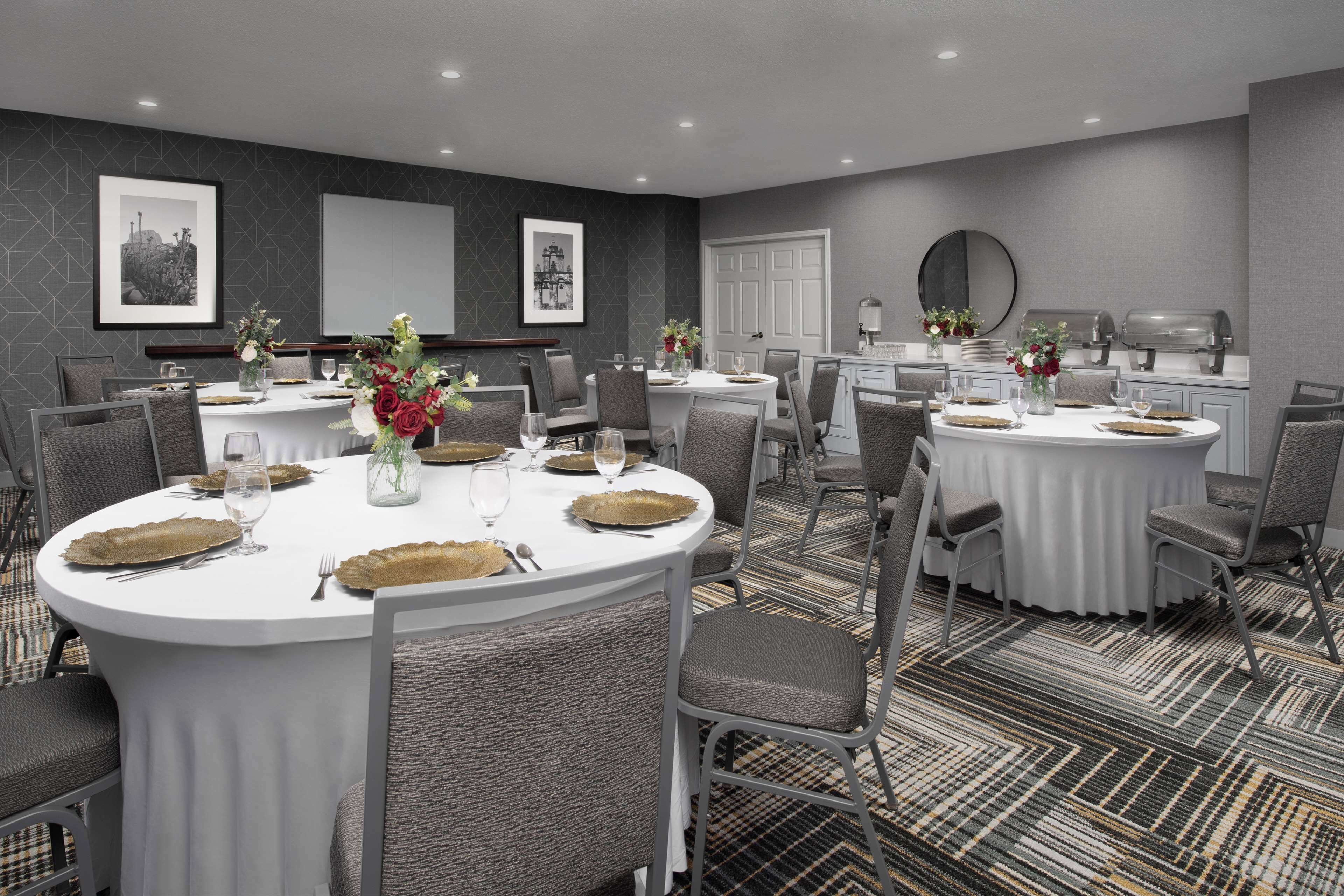 A conference room with round tables, grey upholstered chairs, and a patterned carpet.