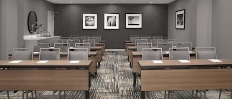 A conference room with multiple tables and chairs, a large mirror, and framed pictures on the wall.