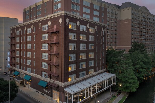 A multi-story hotel with a brick facade, large windows, and a covered entrance area.