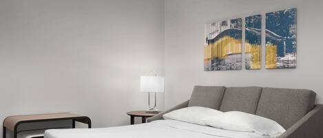 A hotel room with a single bed, a nightstand, a lamp, and a small table.