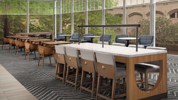 Una sala de conferencias moderna con ventanas amplias, mesas y sillas de madera.