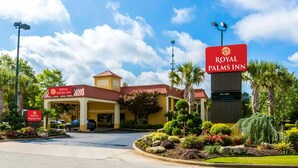 The exterior of the Royal Palms Inn, featuring a prominent entrance with a red roof, a welcoming sign, and landscaped gardens. - Royal Palms INN (Stockbridge)