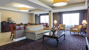 A hotel lobby with a reception desk, sofas, armchairs, a coffee station, and large windows. - Royal Palms INN (Stockbridge)