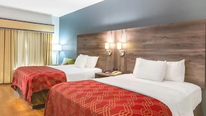 A hotel room with two beds, wooden headboard, bedside lamps, and a window with curtains. - Royal Palms INN (Stockbridge)