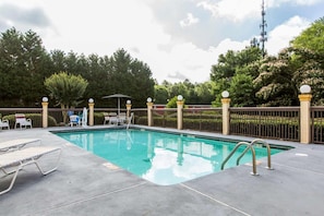 A swimming pool with lounge chairs and a fence. - Royal Palms INN (Stockbridge)