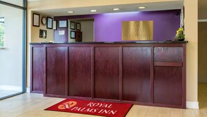 A reception desk with a purple wall and a sign that reads "Royal Palms Inn." - Royal Palms INN (Stockbridge)