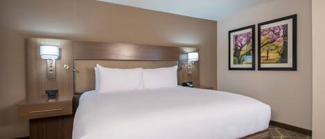 A hotel room with a large bed, two bedside tables with lamps, and two framed pictures on the wall.