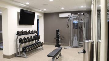 Un gimnasio con banco, mancuernas y una estructura para sentadillas.