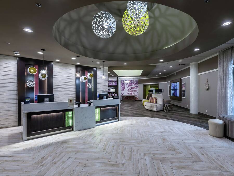 Un vestíbulo amplio con una mesa de recepción, iluminación colgante moderna y un patrón de suelo en espiga.