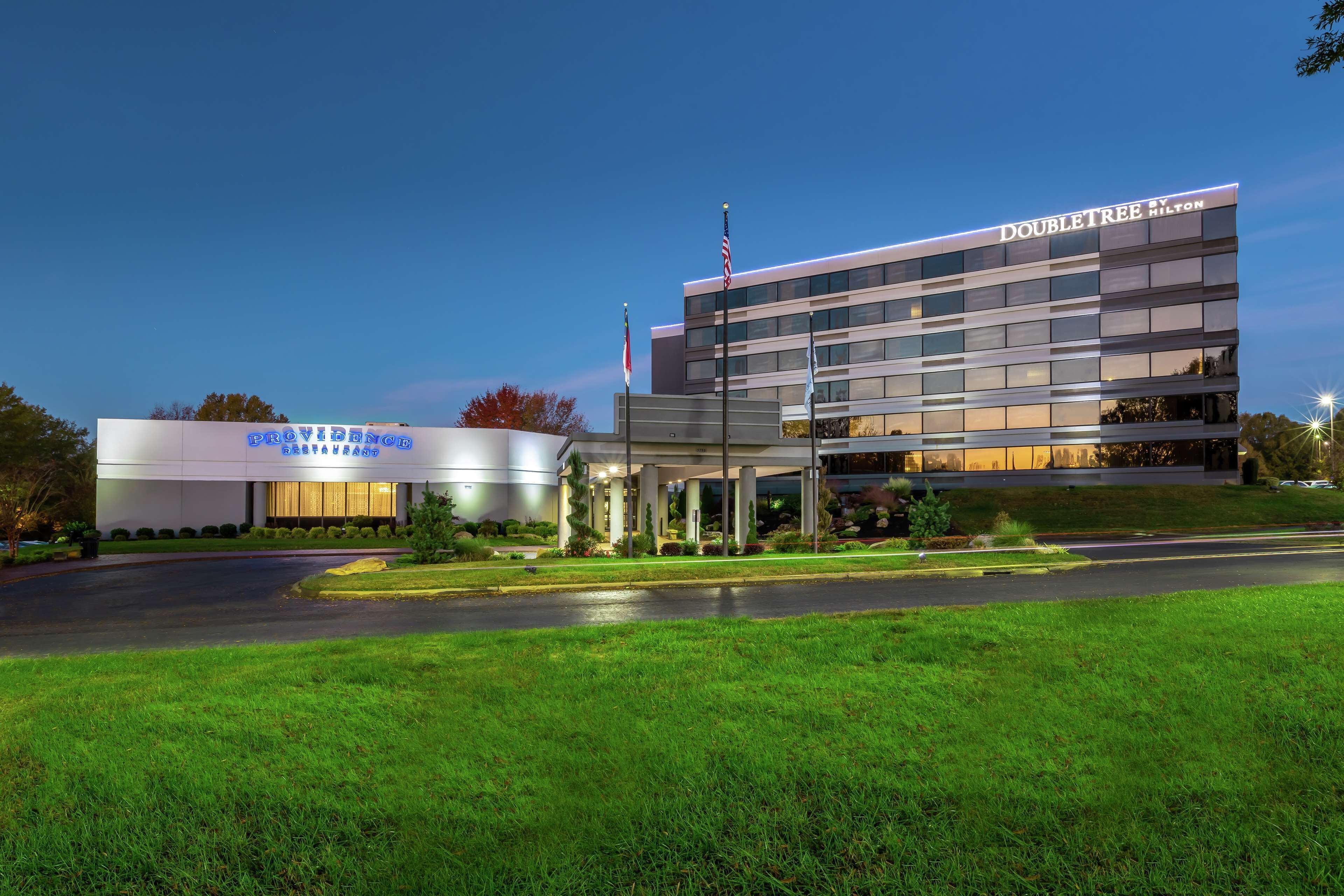 A modern hotel with a prominent "DoubleTree" sign, a covered entrance, and a well-maintained lawn.