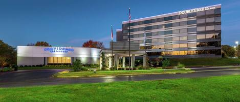 A modern hotel with a prominent "DoubleTree" sign, a covered entrance, and a well-maintained lawn.