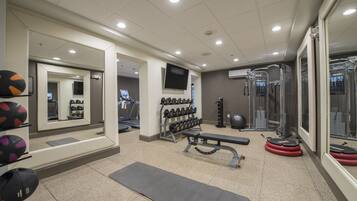 Une salle de sport équipée de matériel d’exercice, d’un téléviseur et d’un miroir.