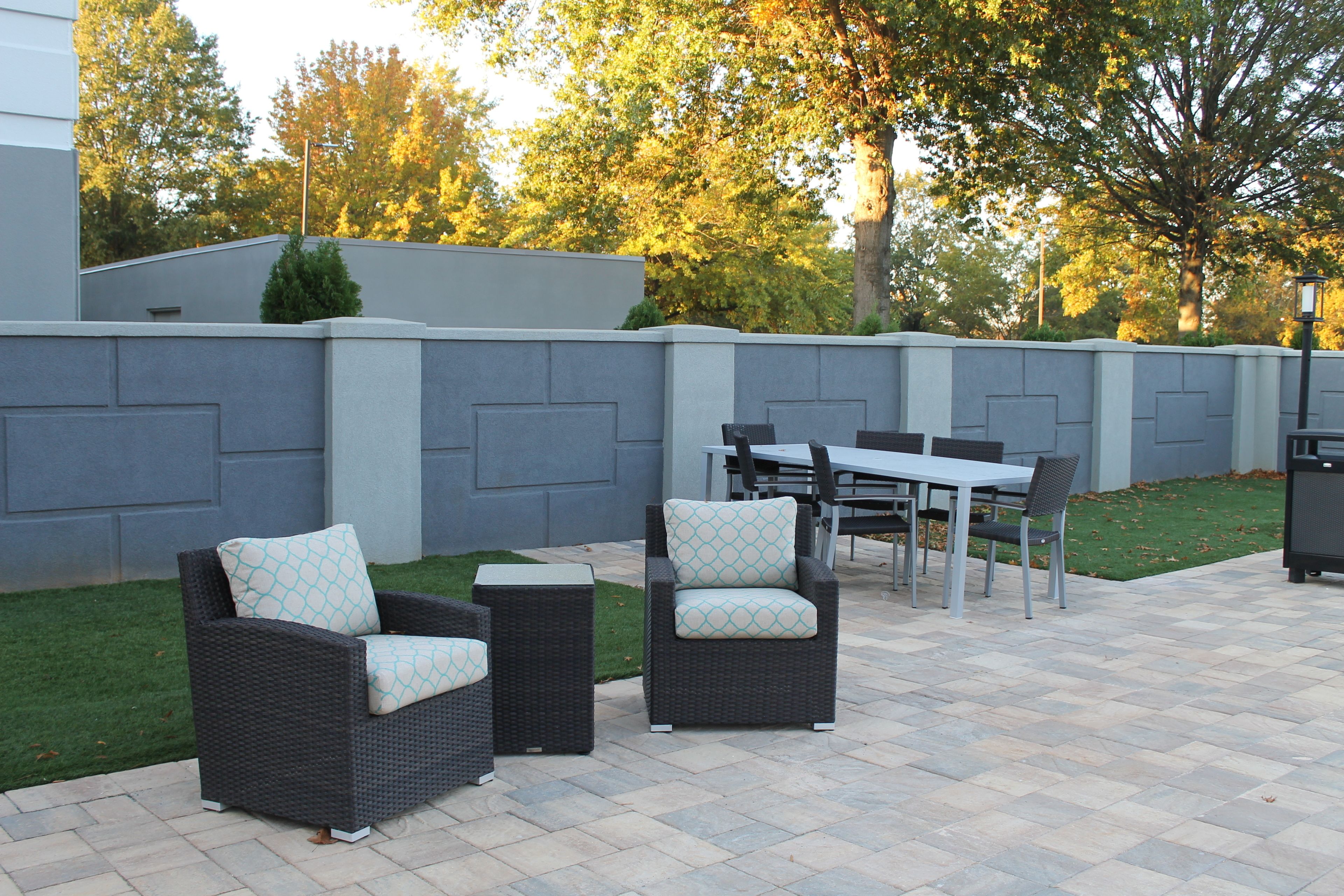 An outdoor patio area with wicker furniture, a table, and chairs.