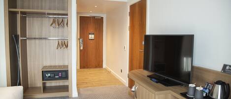 A hotel room with a wooden wardrobe, a television, a coffee maker, and a microwave.