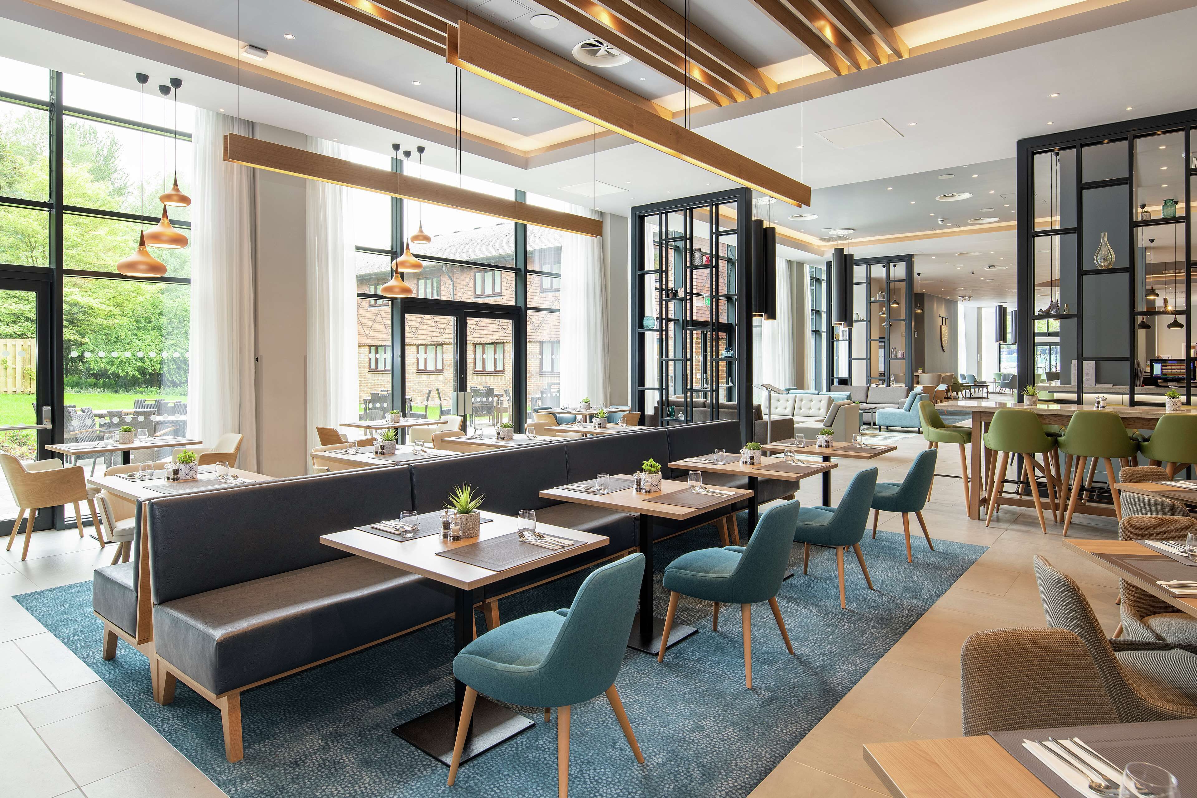 A modern restaurant with high ceilings, large windows, and a mix of seating options including booths and tables.