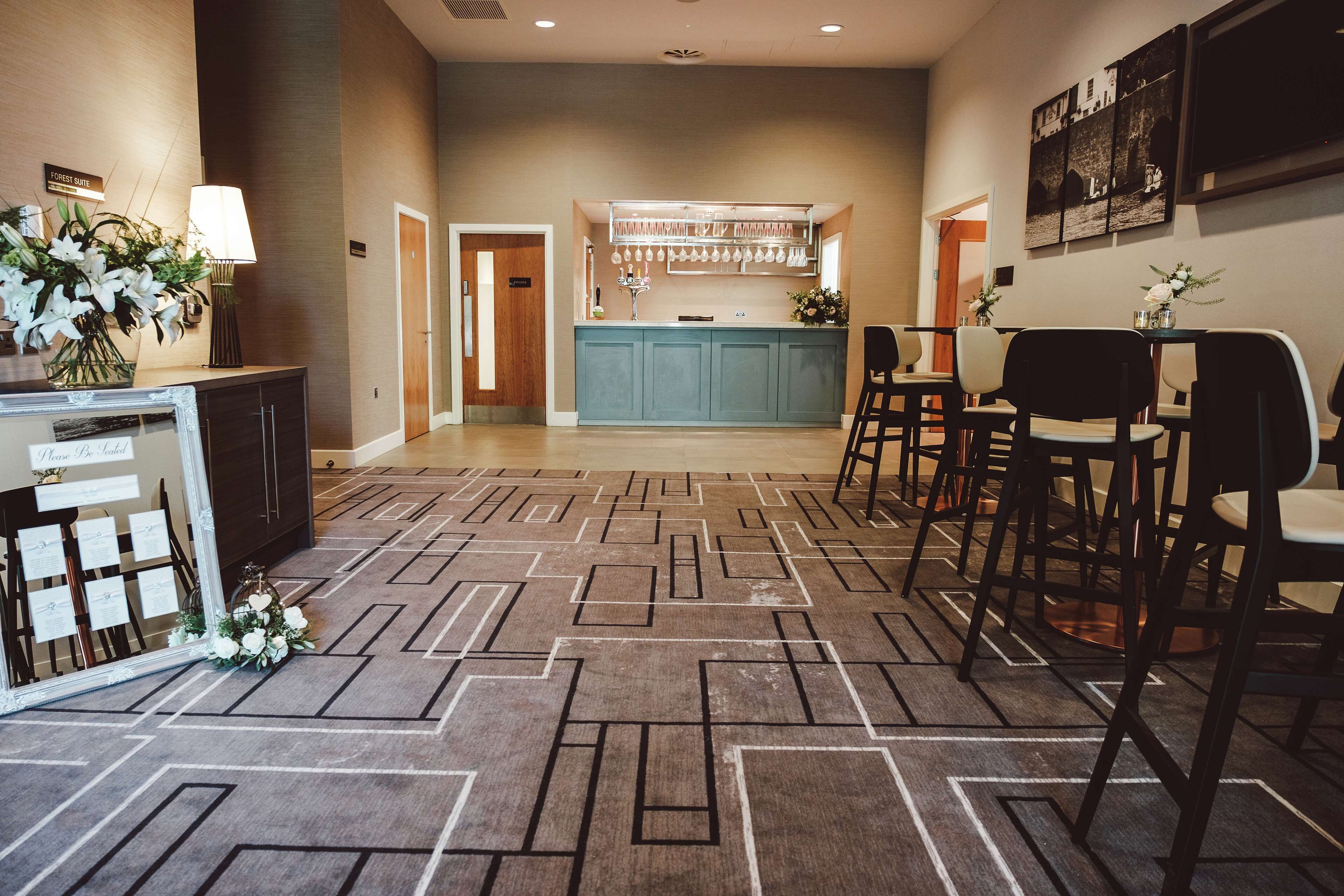 A hotel lobby with a reception desk, seating area, and a bar.