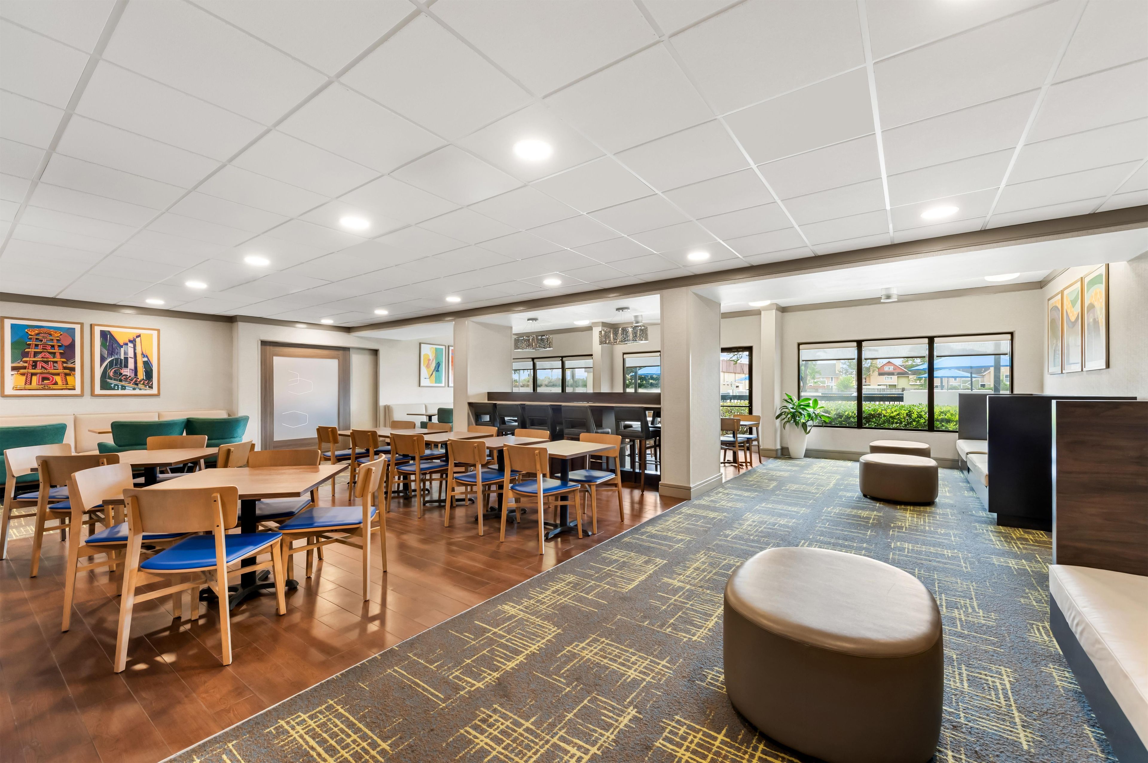 A spacious indoor area with multiple seating arrangements, including tables and chairs, and a carpeted floor.
