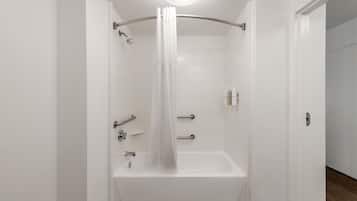 A modern bathroom with a bathtub, shower, and handrails.