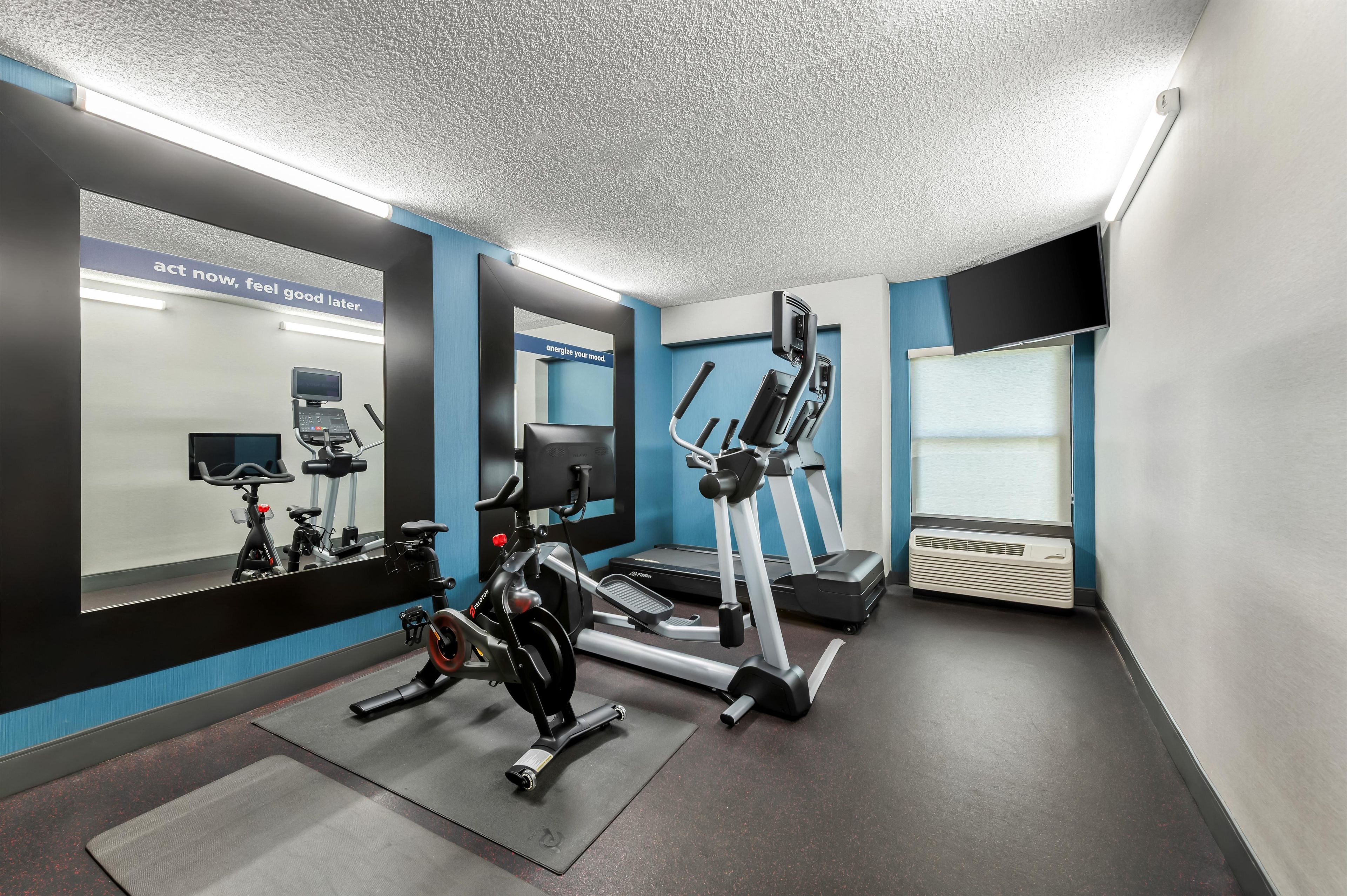 A gym with exercise equipment, a mirrored wall, and motivational posters.