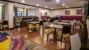 Un comedor moderno con varias mesas y sillas, una barra central y obras de arte en las paredes.