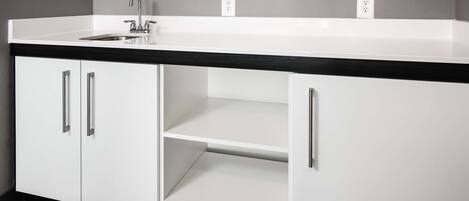 Una cocina moderna con encimera blanca, salpicadero negro y electrodomésticos de acero inoxidable.