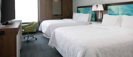 A hotel room with two beds, a TV, a desk, and a chair.