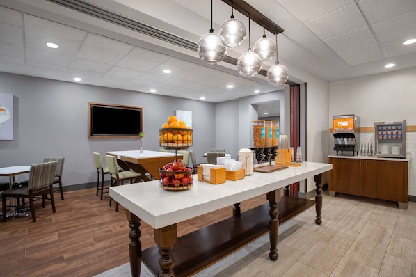 Habitación de hotel con comedor, estación de café y un ventanal grande.