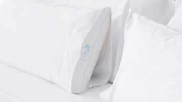 A white bed with pillows, one of which has a 'Pure' logo.