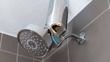 A modern showerhead with a curved design, mounted on a wall with a white textured surface.