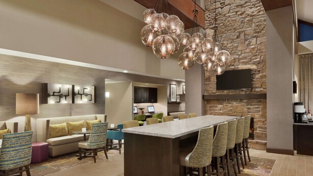 A spacious lounge area with a long bar, comfortable seating, and a stone accent wall. - Hampton Inn & Suites Springdale (Springdale)