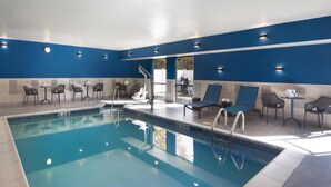 A swimming pool with lounge chairs and tables, surrounded by blue walls and recessed lighting. - Hampton Inn Youngstown/Boardman (Poland)