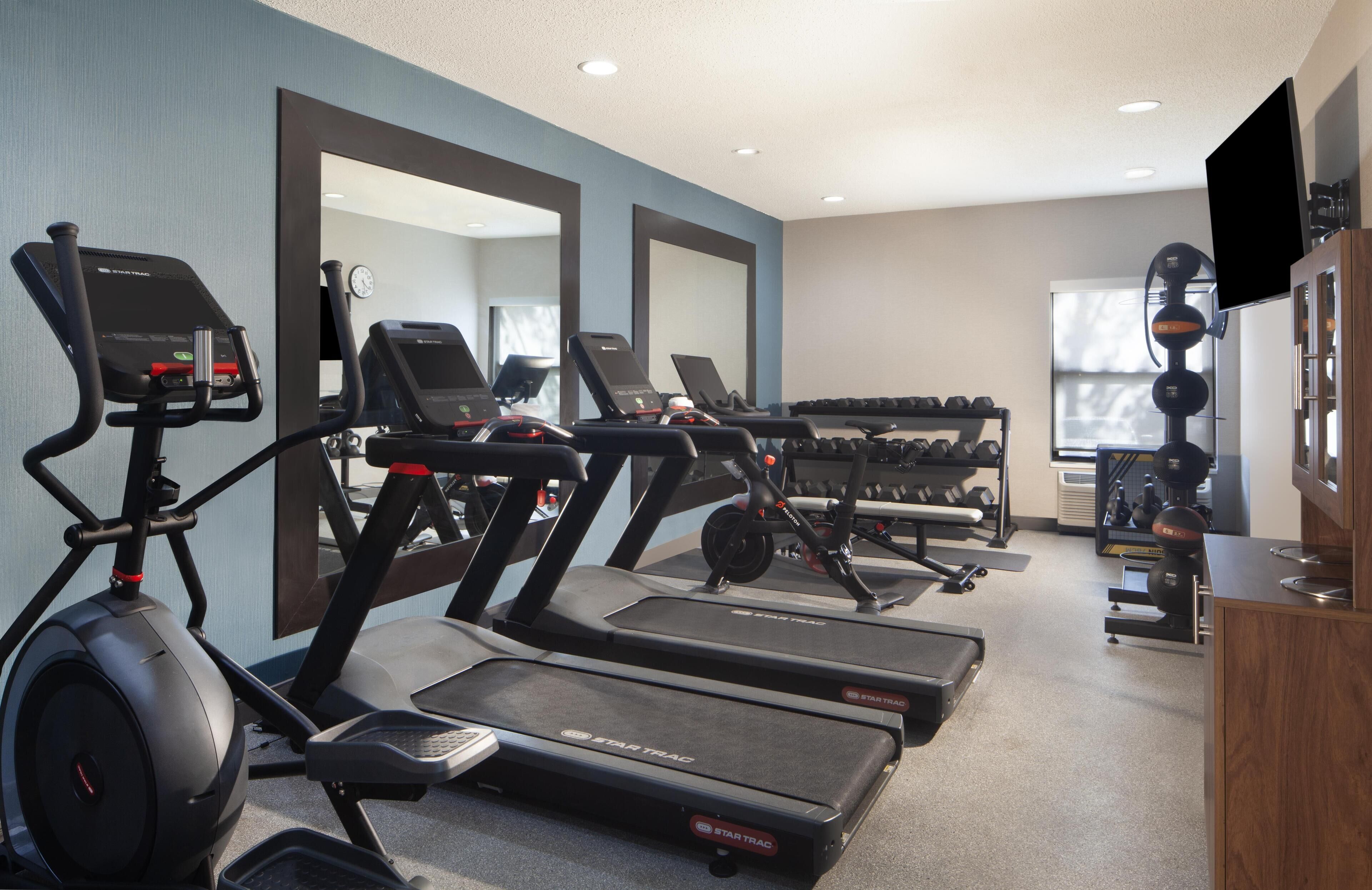 A gym with treadmills, dumbbells, and exercise equipment.
