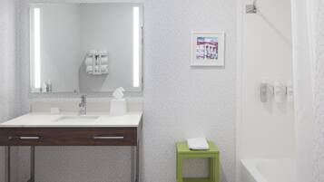 A modern bathroom with a white sink, a mirror, a green stool, and a shower curtain.