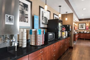 Een moderne keuken met een koffieapparaat, magnetron en koelkast.
