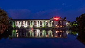 A hotel with a reflection in the water, featuring a prominent neon sign. - Hampton Inn Bonita Springs/Naples-North (Bonita Springs)