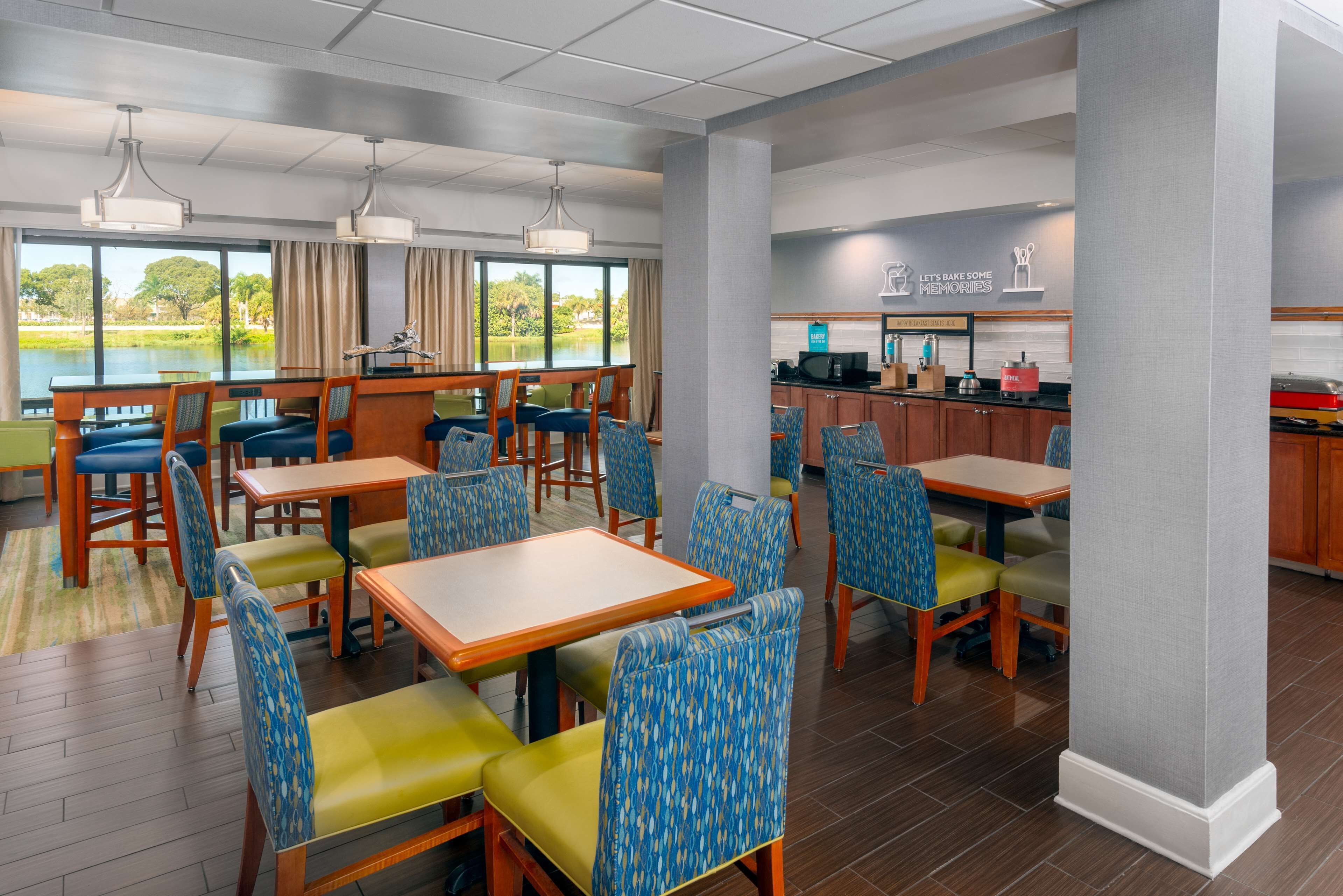 A dining area with tables and chairs, a kitchen area, and a view of a lake.