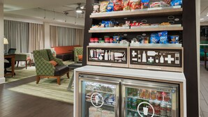 A hotel lobby with seating, a snack display, and beverage dispensers. - Hampton Inn Bonita Springs/Naples-North (Bonita Springs)