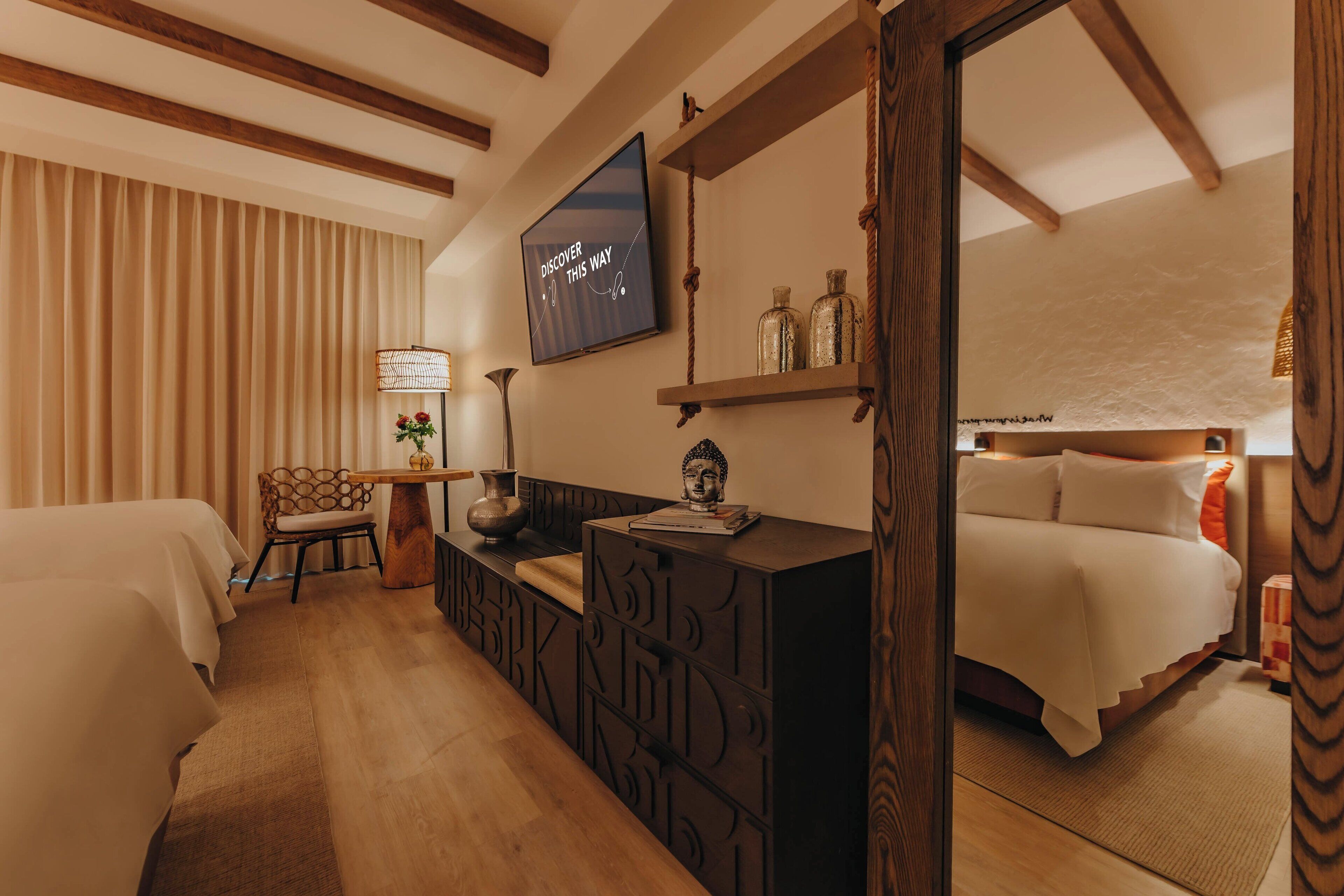 Habitación de hotel con una cama, un escritorio con computadora, una silla, un televisor y una ventana con cortinas.