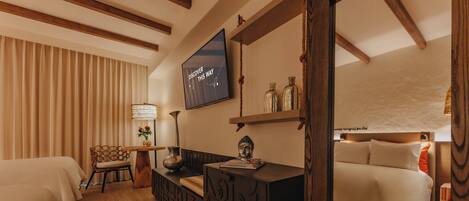 Habitación de hotel con una cama, un escritorio con computadora, una silla, un televisor y una ventana con cortinas.