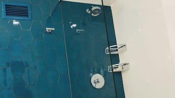 A bathroom with a glass-enclosed shower, a white toilet, and a blue hexagonal tile wall.