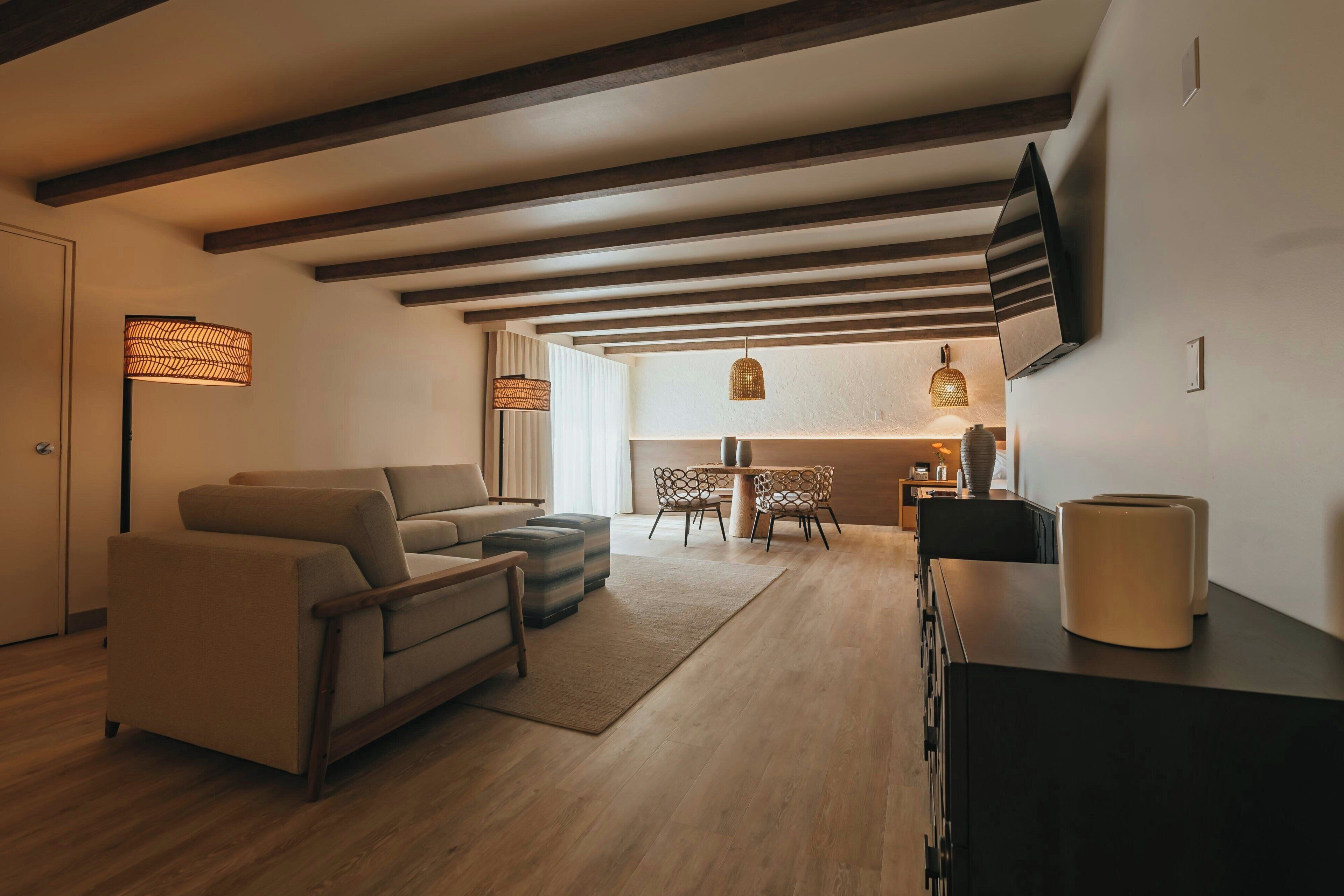 A modern living room with a sofa, ottoman, and a dining area with chairs and a table.