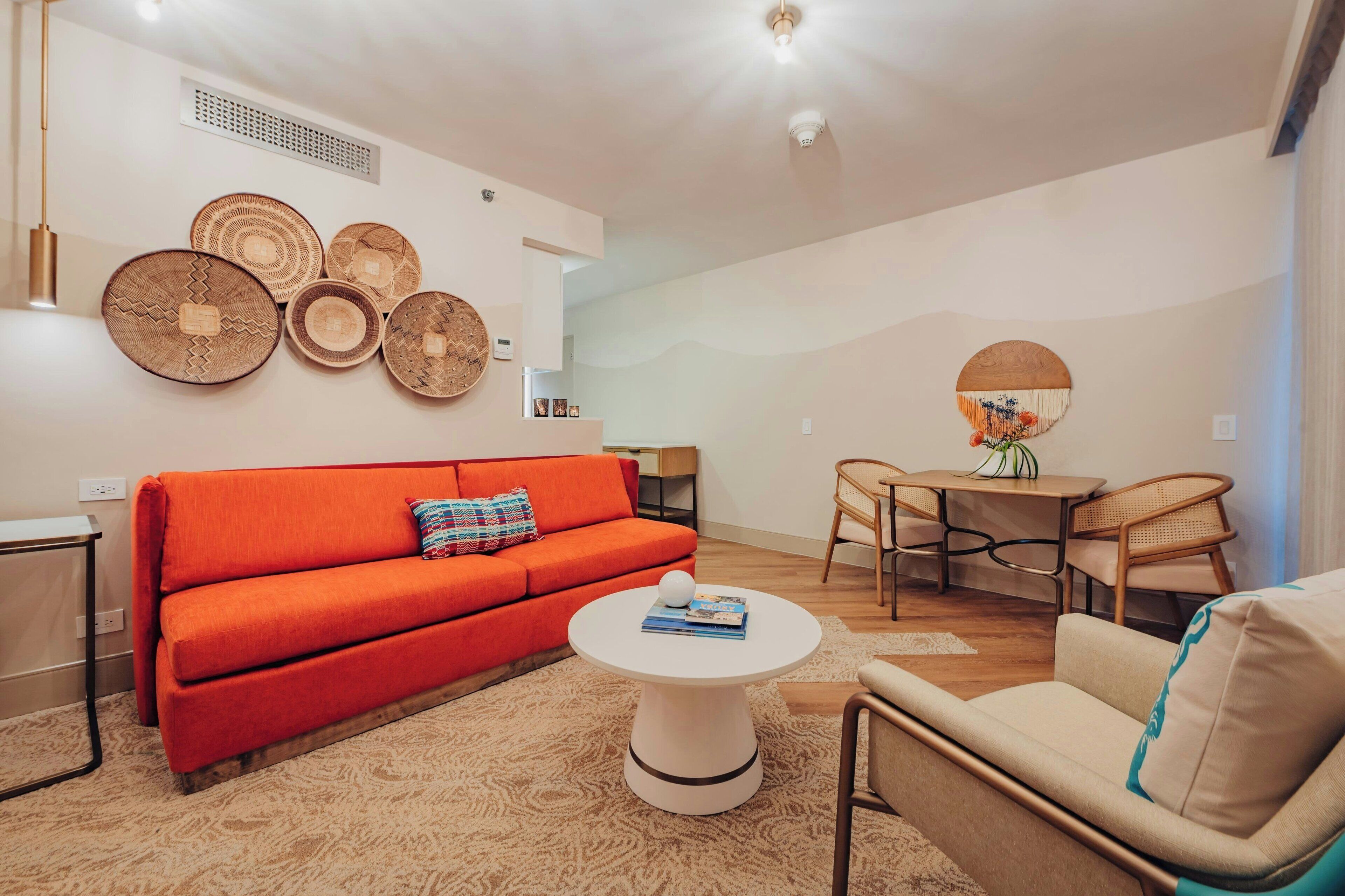 Een moderne woonkamer met een rode bank, een witte salontafel, en een eethoek met een houten tafel en stoelen.