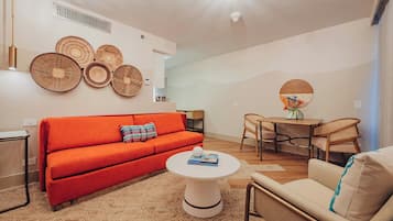 Een moderne woonkamer met een rode bank, een witte salontafel, en een eethoek met een houten tafel en stoelen.
