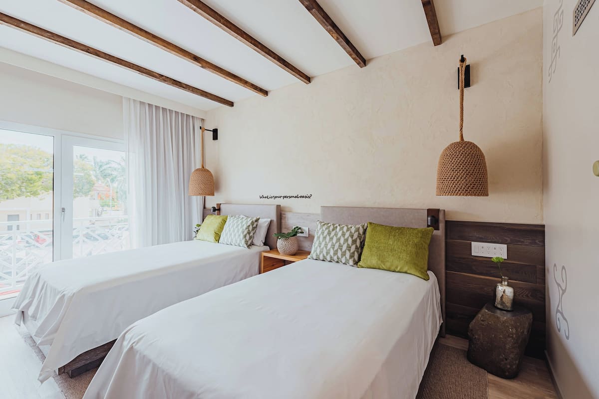 A hotel room with two beds, a large window, and a view of the outside.